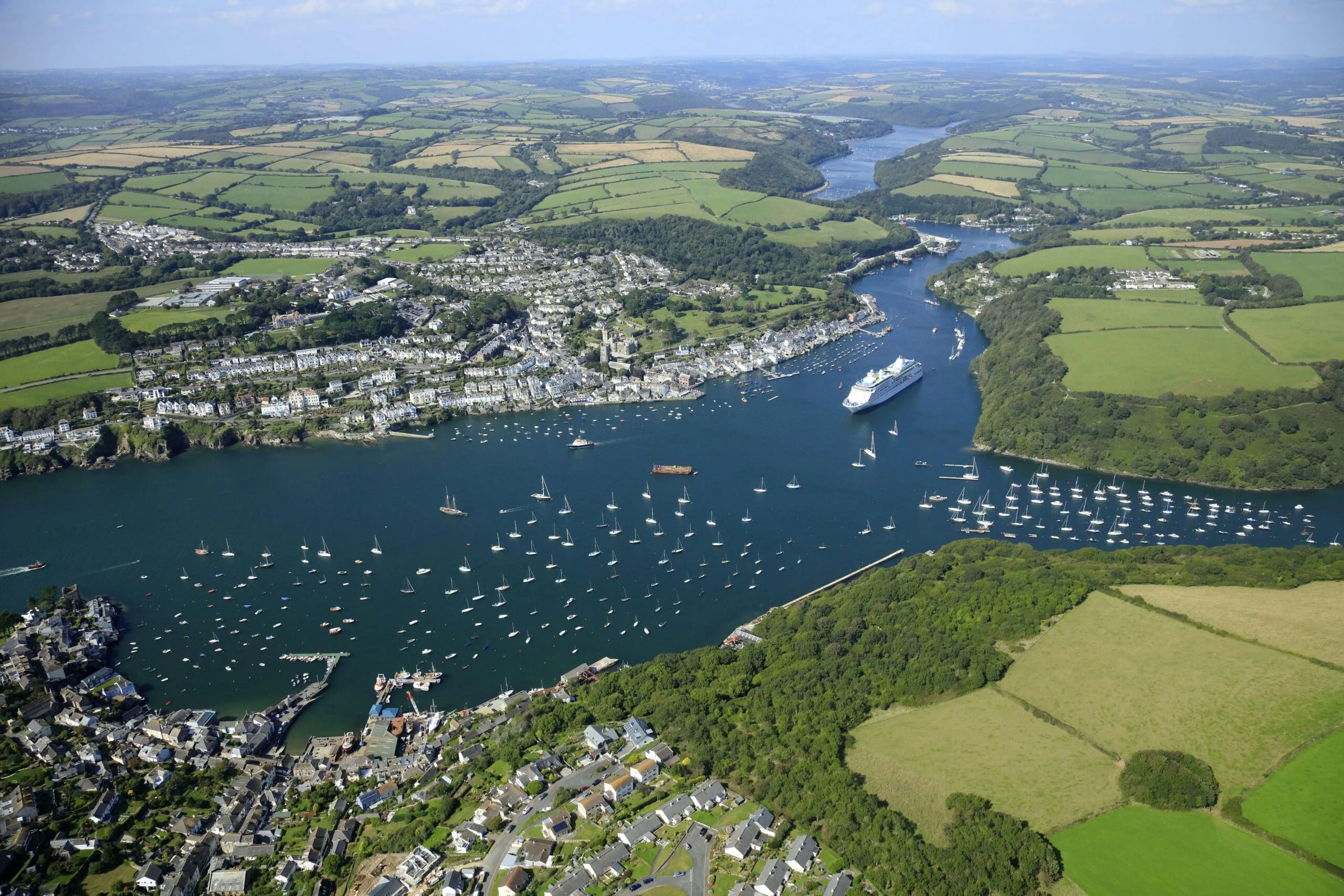 An aerial view of Fowey, in South Cornwall, with its harbour and sailboats and ships lying at anchor at the mouth of the rover